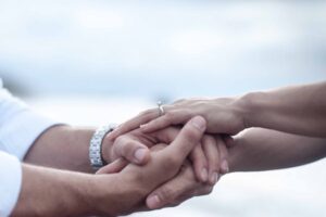 Close-up of a couple holding hands outdoors, showcasing love and commitment with rings.